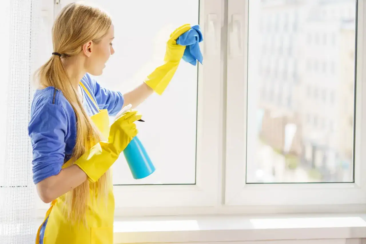 Kobieta myjąca białe okna plastikowe w pochmurny dzień