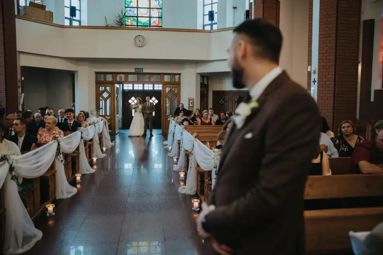 Narzeczona idzie do ołtarza w kościele, gdzie czeka pan młody. To piękny moment przed ślubem, który zapoczątkuje ich wspólne życie.