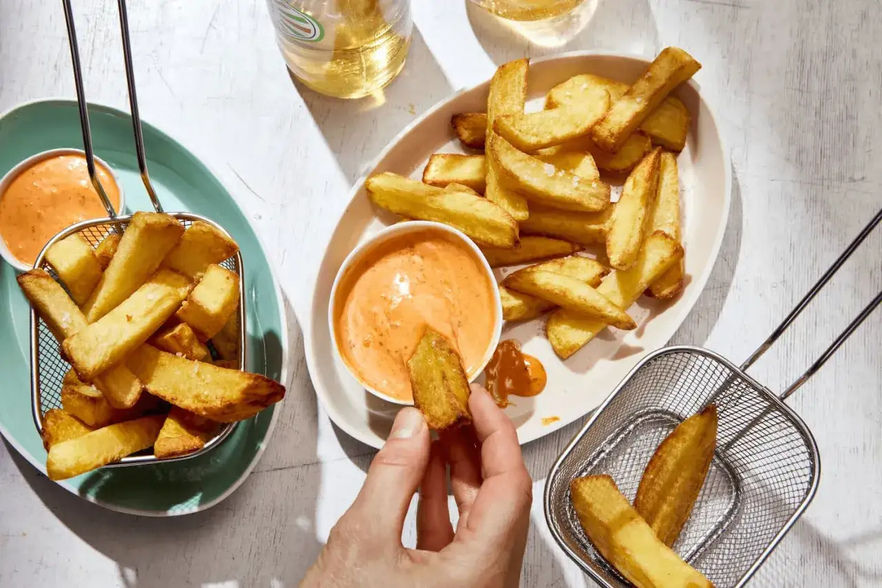 Goldbraune belgische pommes, knusprig und salzig, werden in eine cremige Sauce getunkt. Ein Genuss!
