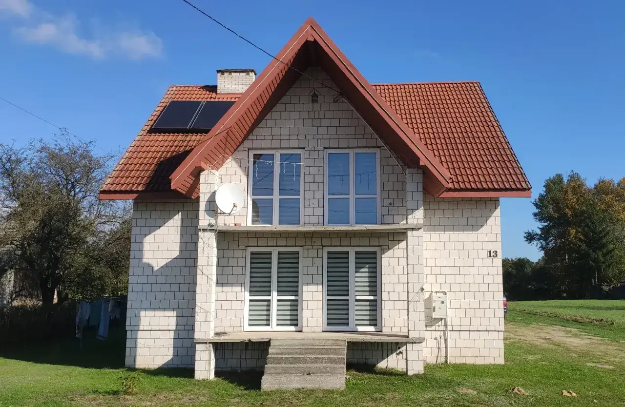 Dom z panelami słonecznymi i anteną satelitarną. Dowiedz się, ile kosztuje audyt energetyczny czyste powietrze, by poprawić efektywność domu.