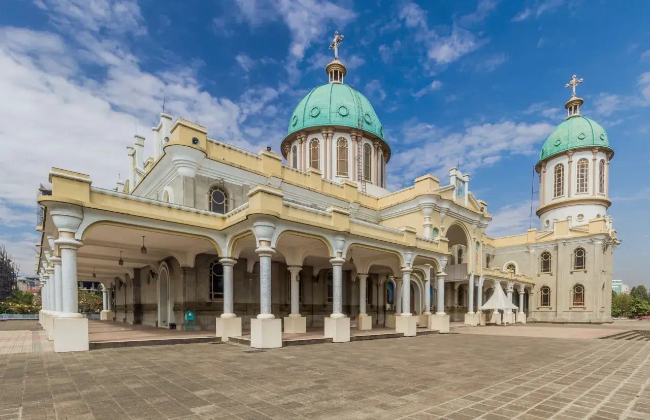 Katedra Świętej Trójcy w Addis Abebie, z zielonymi kopułami i kolumnowym portykiem, pod błękitnym niebem.