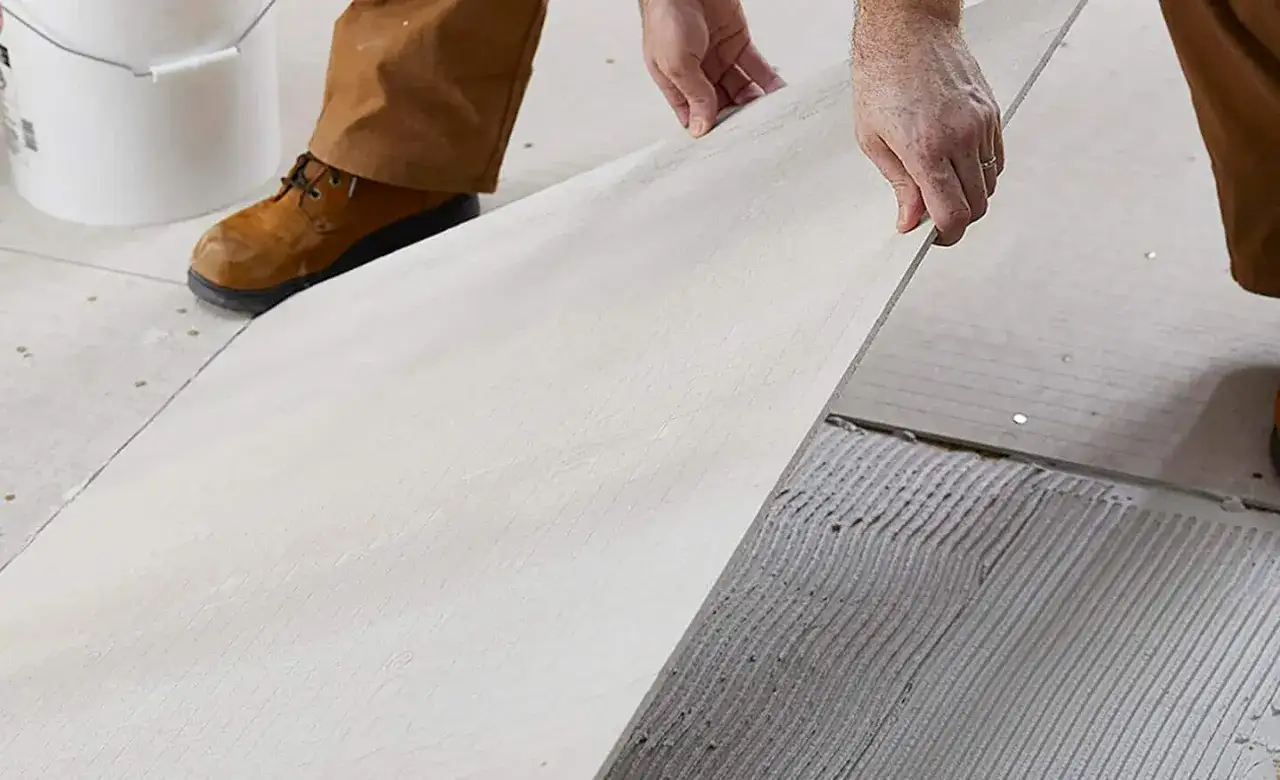 Hands place cement board onto a bed of thinset for a strong tile foundation.