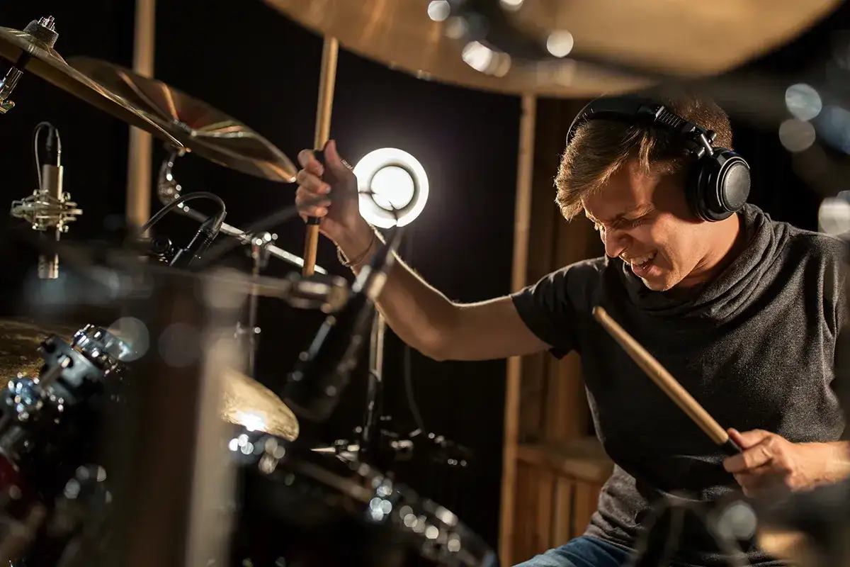 Un batteur concentré, casque sur les oreilles, joue avec passion. Il espère ne pas avoir d'acouphène après la boîte de nuit.