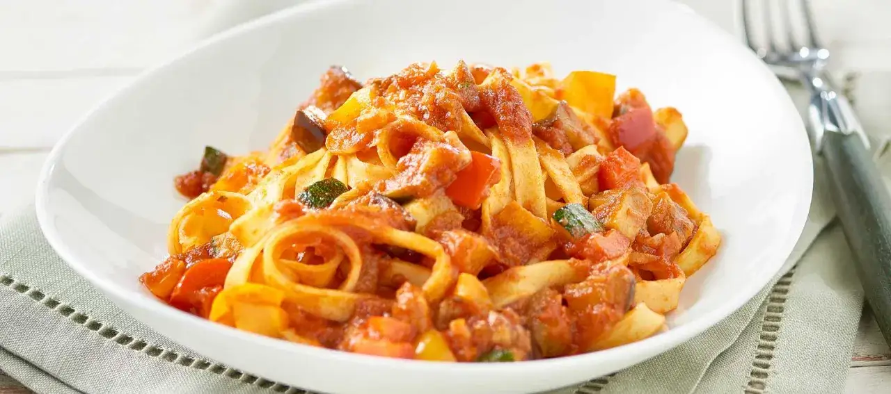 Tagliatelle condite con un ricco sugo alla bolognese, ricco di verdure colorate come peperoni e zucchine.