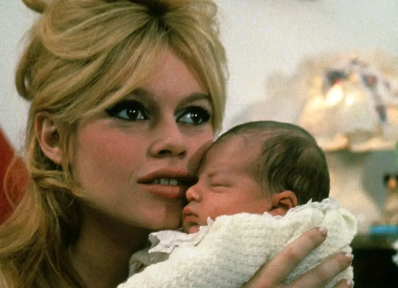Brigitte Bardot czule tuli swojego syna, Nicolasa Charriera, otulonego w biały kocyk.