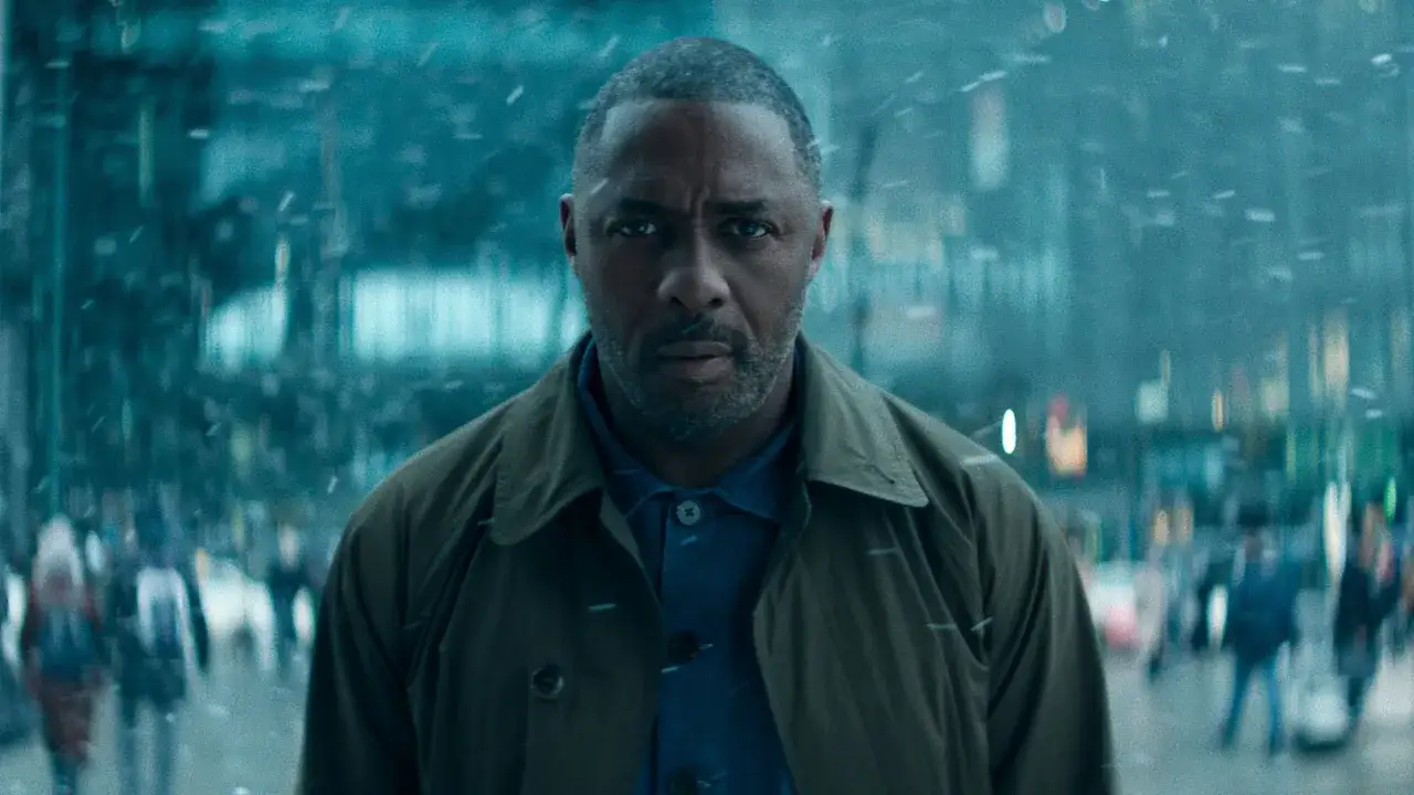 Idris Elba w deszczu, zastanawia się, co obejrzeć na Apple TV. Mroczna atmosfera i migoczące światła miasta.