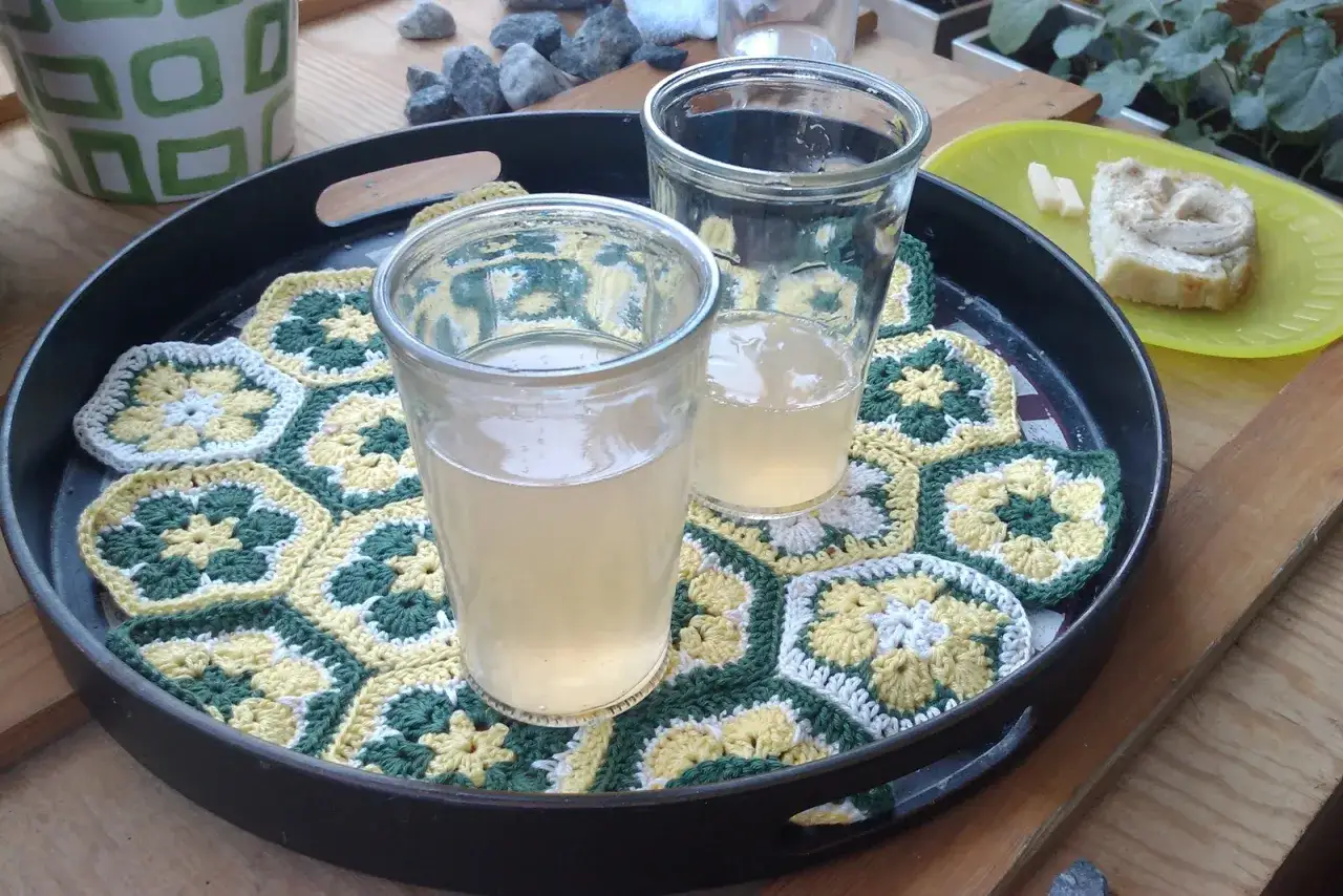 Två glas med rabarberlemonad står på en bricka med virkade hexagoner.