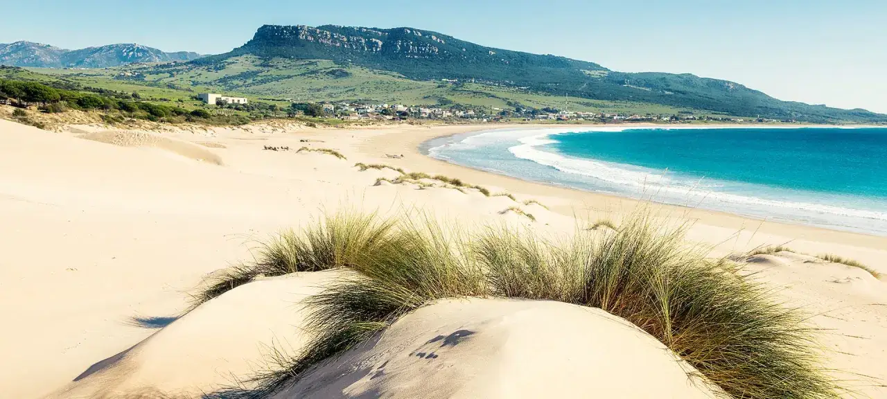 Dzika plaża na Costa de la Luz z wydmami i surferami w tle