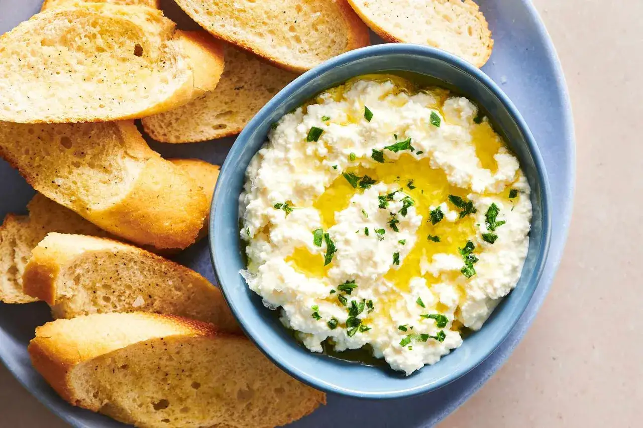 Puszysta ricotta, polana oliwą i posypana natką, czeka na chrupiące grzanki. Idealna przekąska, by dowiedzieć się, ricotta co to.