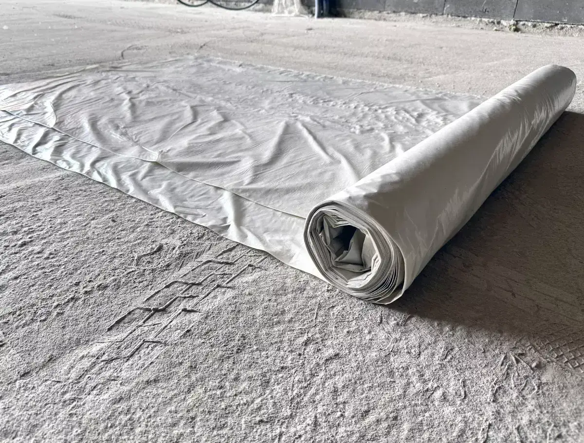 Biała folia rozłożona na świeżo wylanym betonie, chroniąca go przed przymrozkiem.