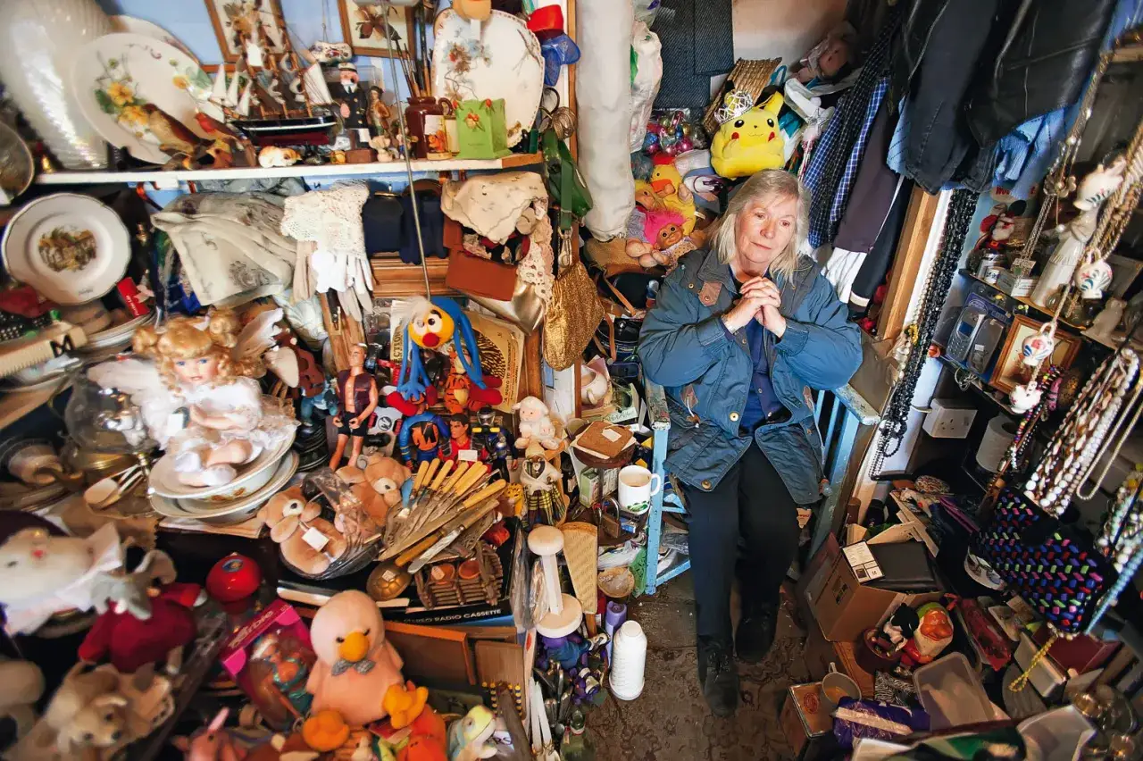 Kobieta siedzi wśród stosów zabawek i bibelotów. Czy to miejsce, gdzie zgłosić zbieractwo?