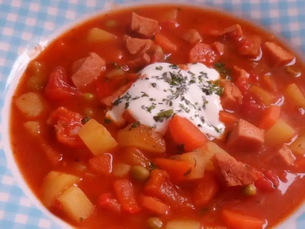 Herzhaftes Wurstgulasch mit Kartoffeln, Karotten und Erbsen, garniert mit einem Klecks saurer Sahne. Ein tolles wurstgulasch rezept f&uuml;r kalte Tage.