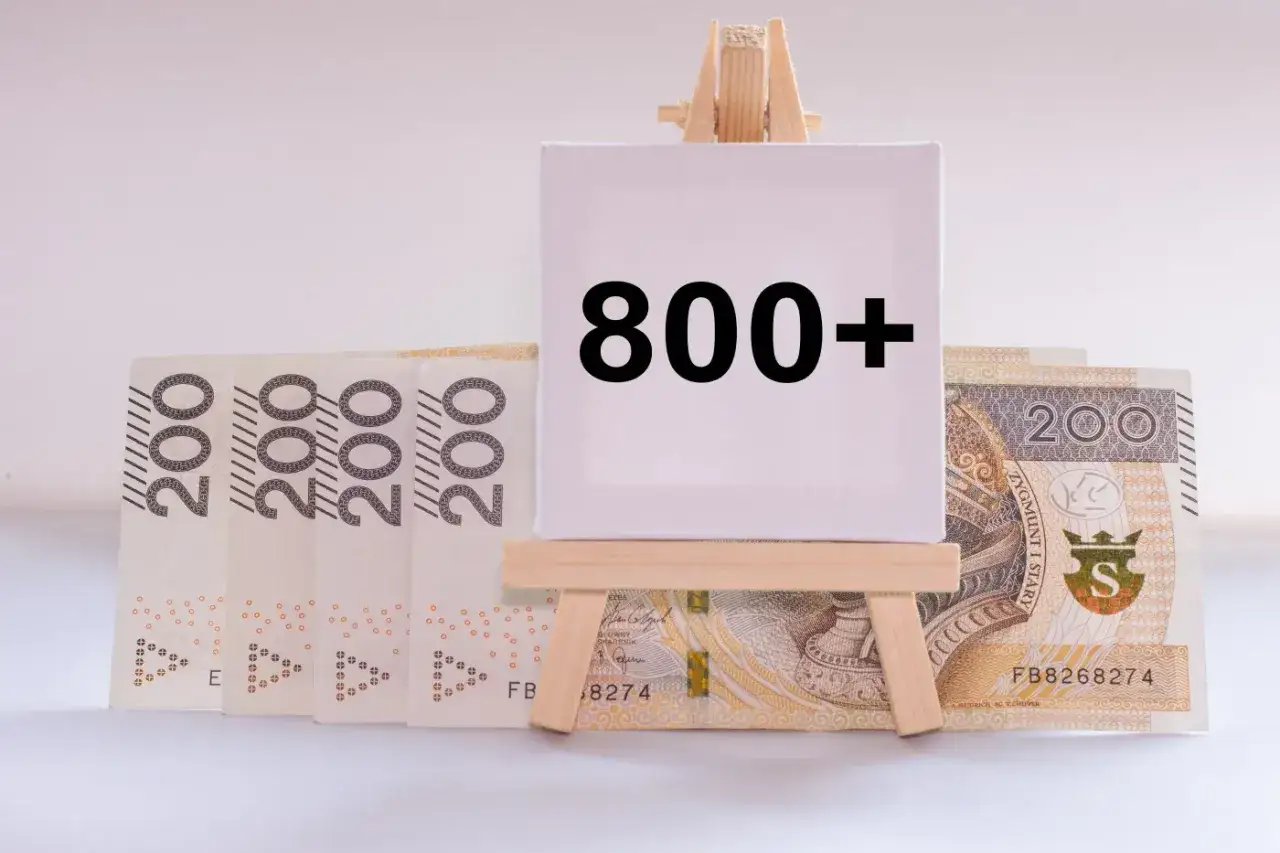 Pieniądze, banknoty 200 zł, stoją za tabliczką z napisem 