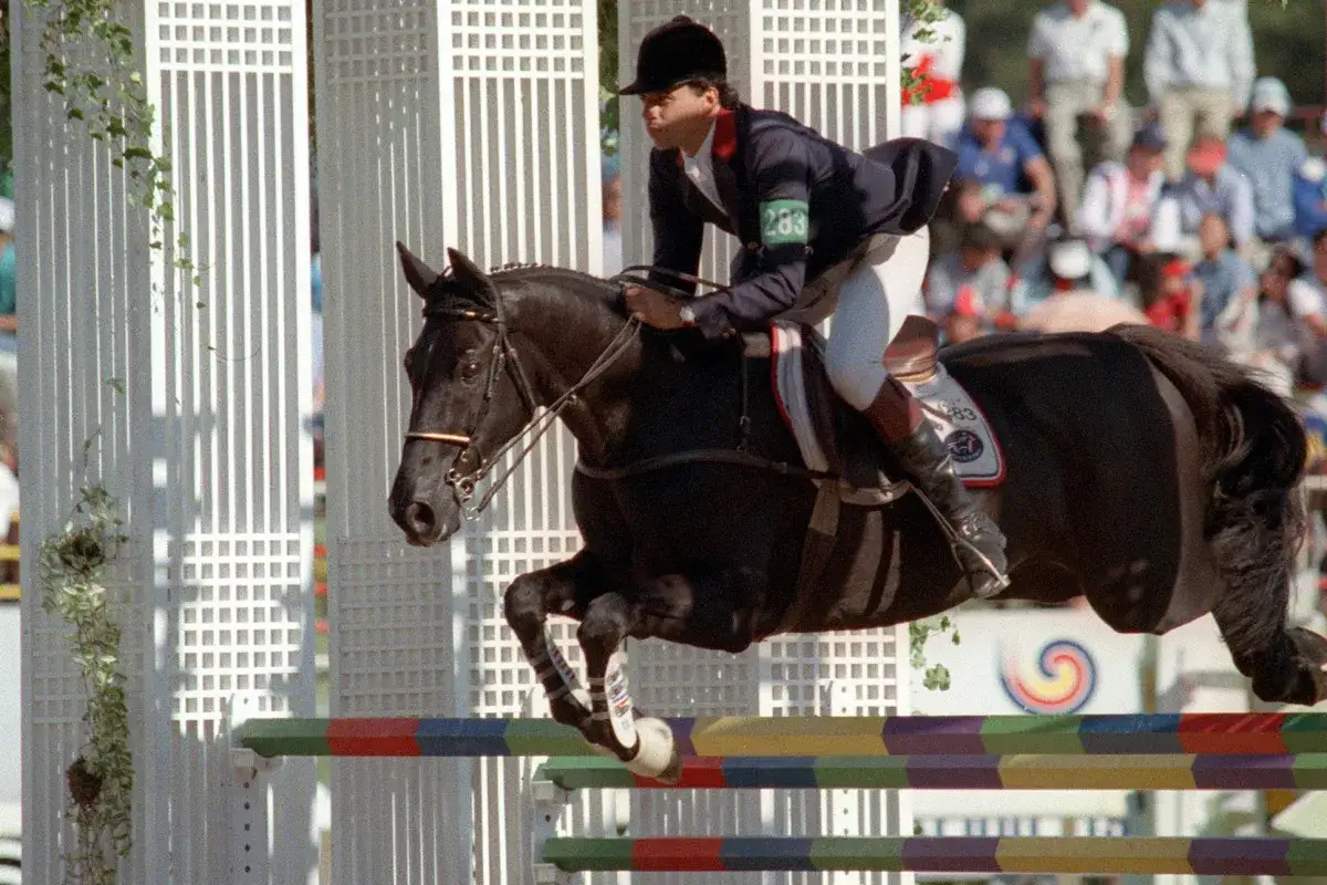 Un cavalier et son cheval noir sautent un obstacle. Le cheval, aussi célèbre que Jappeloup mort, est en plein effort.