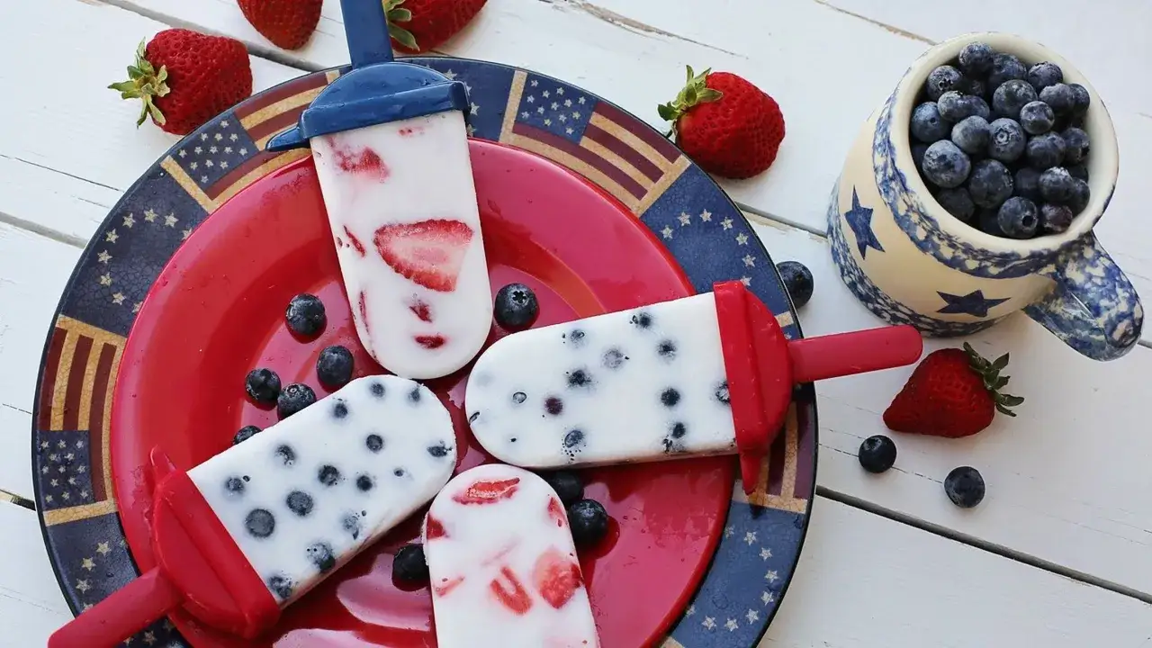 Ghiaccioli fatti in casa con fragole e mirtilli, perfetti per una festa estiva.