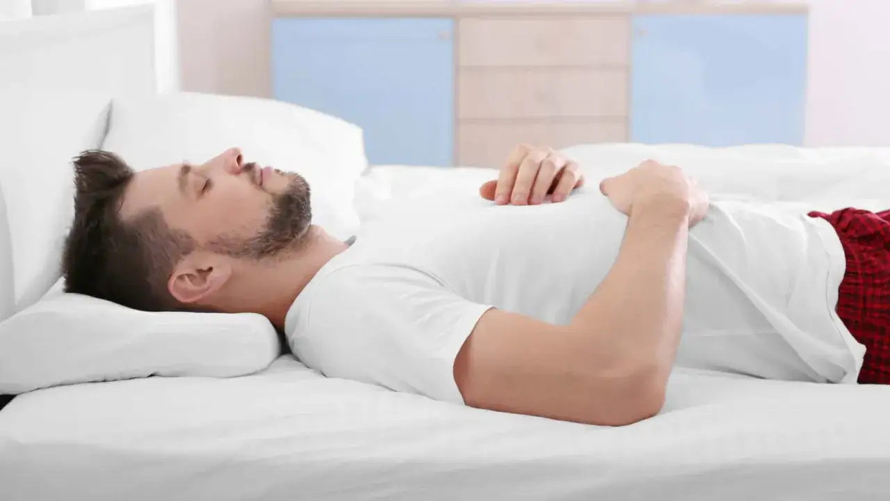 Mann schl&auml;ft auf dem R&uuml;cken, Kopf auf einem Kissen gebettet. Die richtige Schlafposition mit dem passenden Kissen ist wichtig f&uuml;r erholsamen Schlaf.
