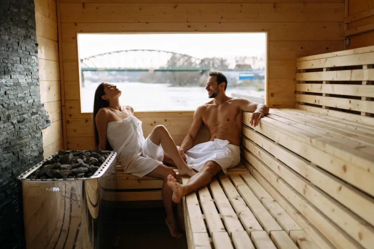Couple relaxant dans un sauna en bois &agrave; Prague, avec vue sur un pont.