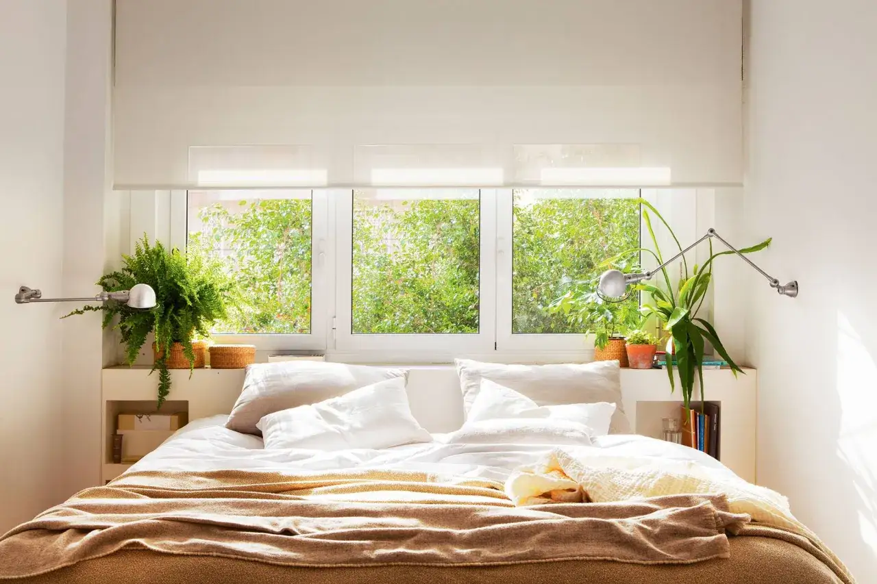 Cama acogedora con plantas para dormitorio, rodeada de luz natural y vegetaci&oacute;n exuberante.