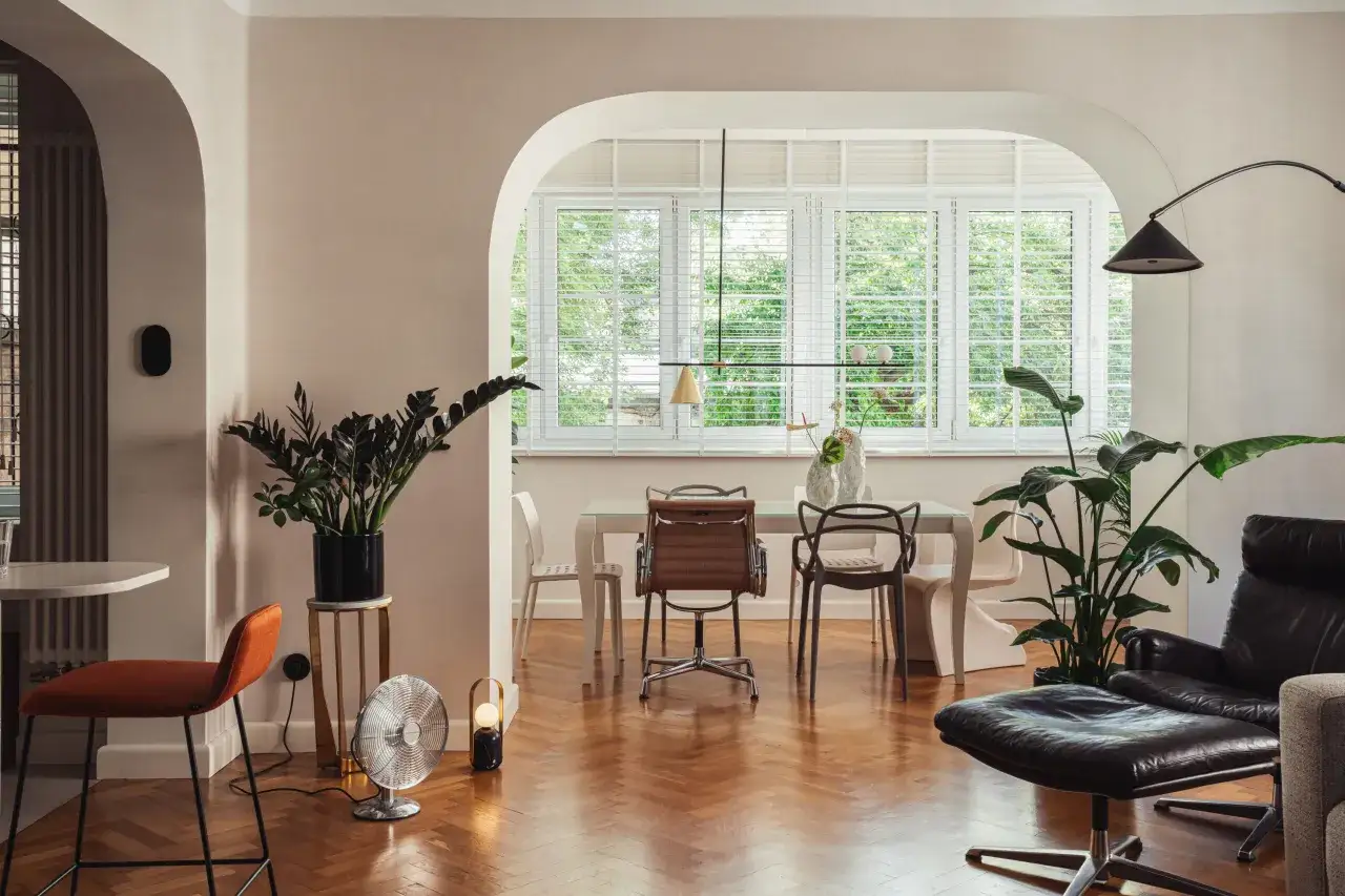 Eklektyczny salon z jadalnią, gdzie nowoczesne meble i rośliny tworzą przytulną atmosferę.
