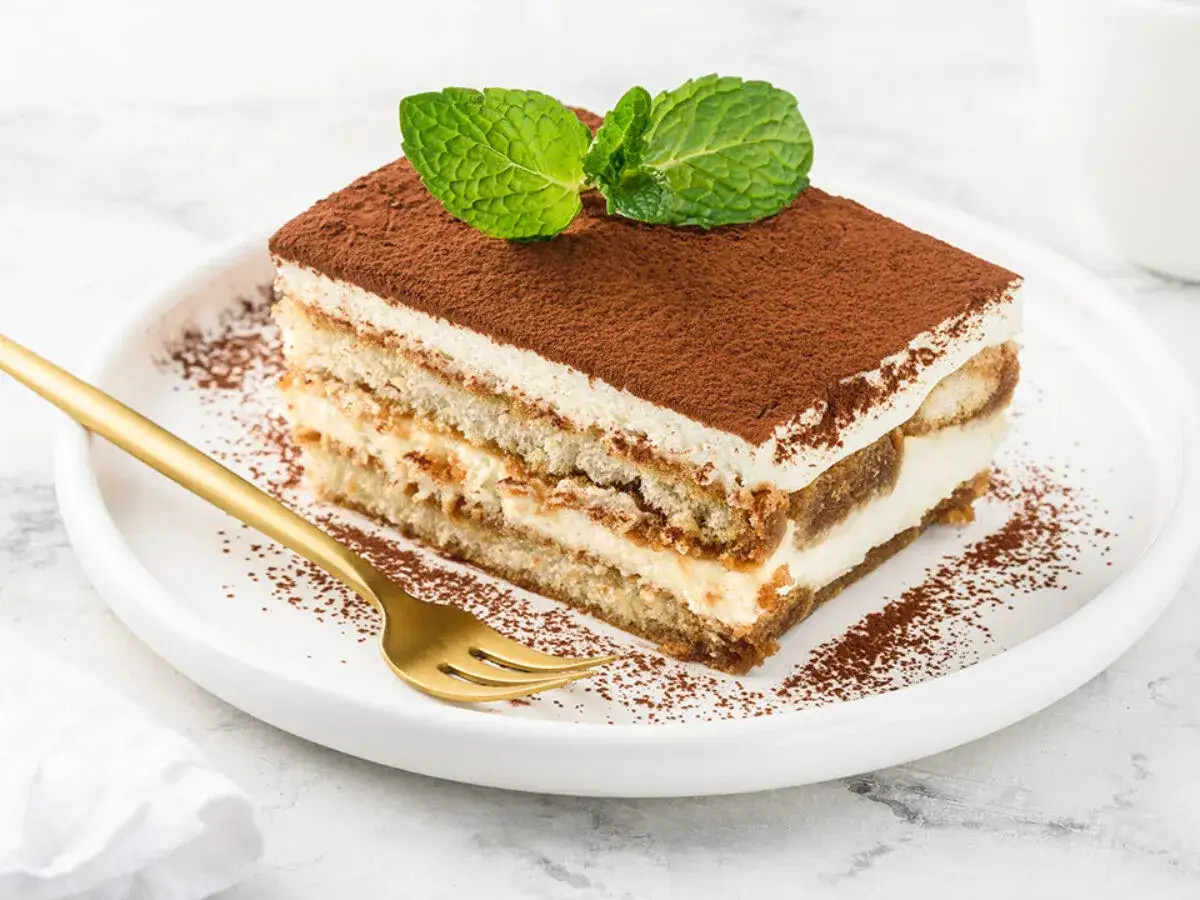 Pyszny kawałek tiramisu z mascarpone, posypany kakao i udekorowany miętą. Idealny na deser, gdy szukasz sprawdzonego przepisu.