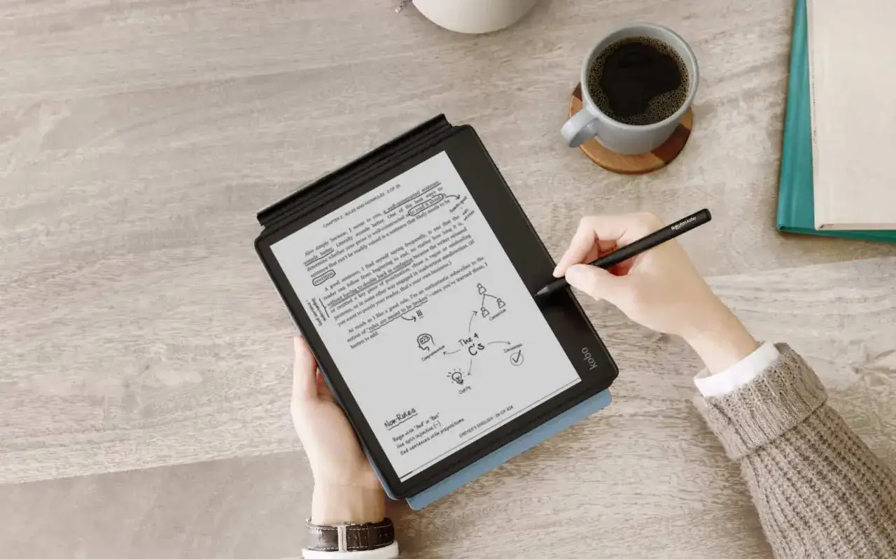 Résumé d'un livre sur une liseuse, avec une tasse de café et un stylet. La personne prend des notes sur le texte.