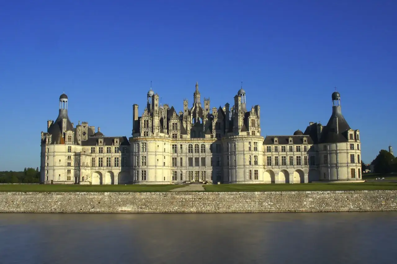 Majestatyczny zamek Chambord, perła Doliny Loary, wznosi się nad spokojną rzeką.
