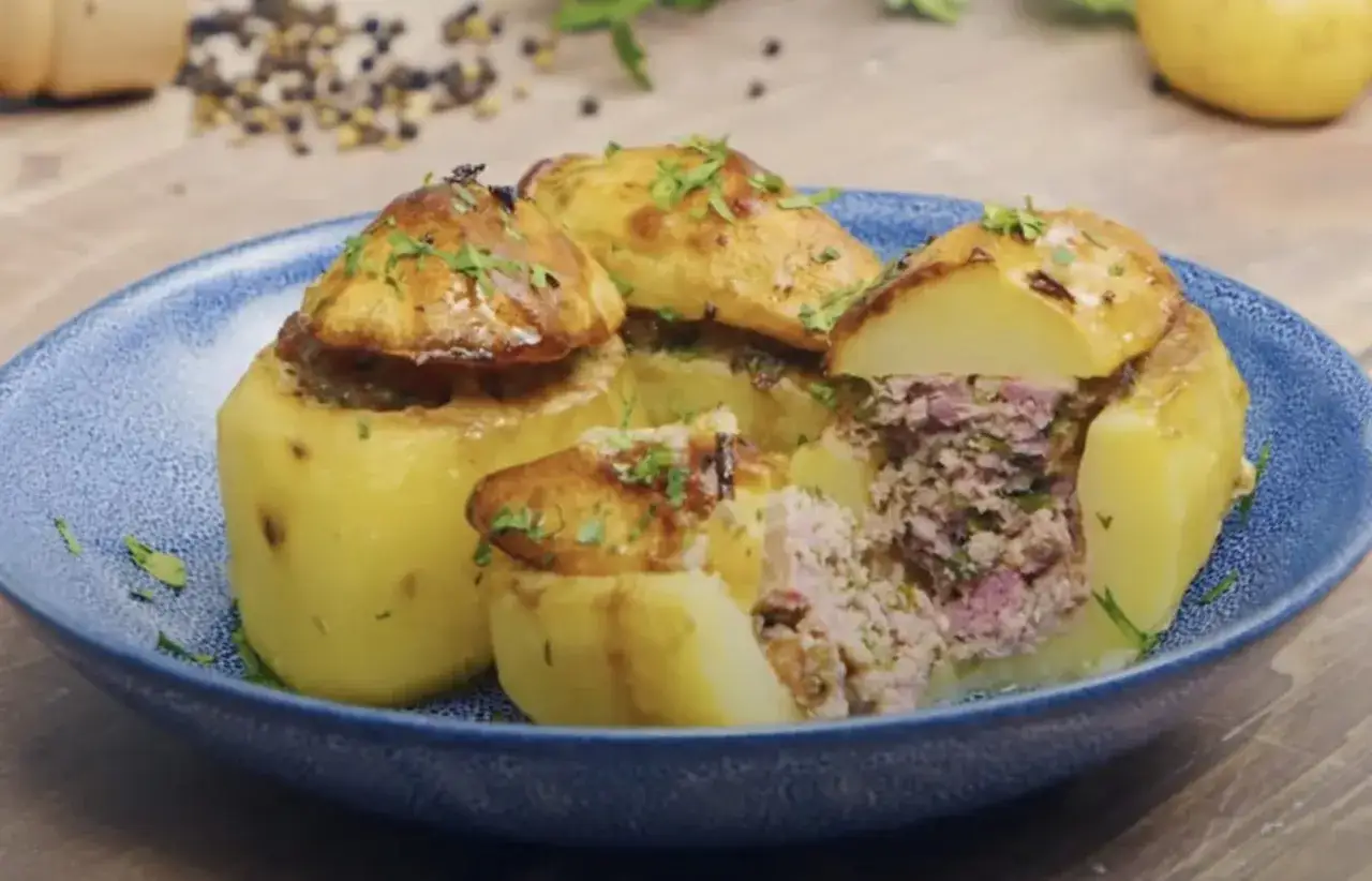 Pommes de terre farcies g&eacute;n&eacute;reusement avec une farce savoureuse, garnies d'herbes fra&icirc;ches et servies dans une assiette bleue.