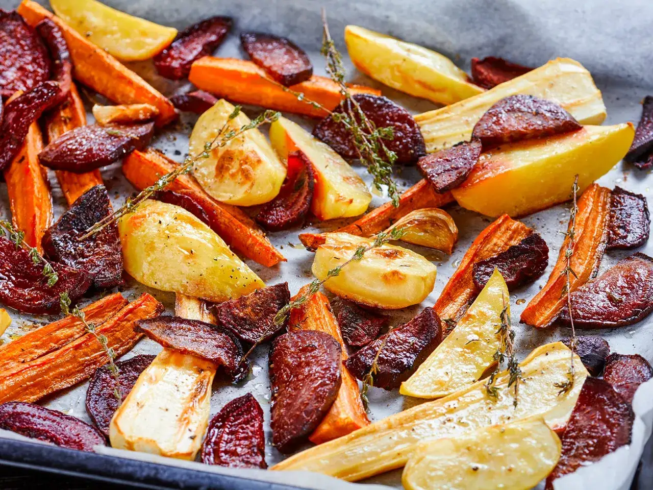 Ger&ouml;stetes Wurzelgem&uuml;se, darunter Rote Bete, Karotten und Pastinaken, mit Kr&auml;utern verfeinert. Perfekt f&uuml;r gesunde rote Bete Rezepte.