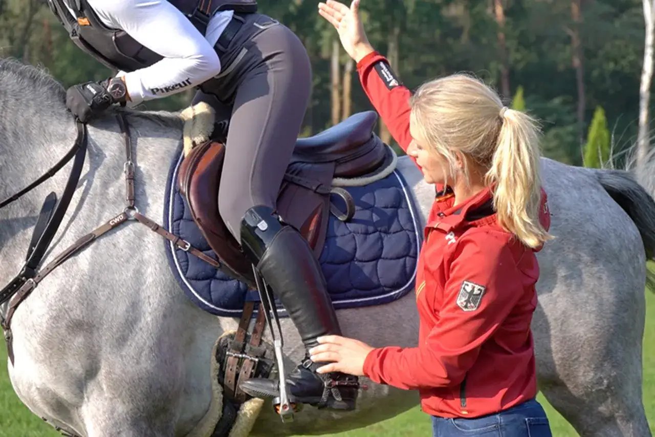 Reitlehrerin gibt Tipps f&uuml;r einen leichteren Sitz beim Reiten. Die Reiterin auf dem Schimmel wird korrigiert.