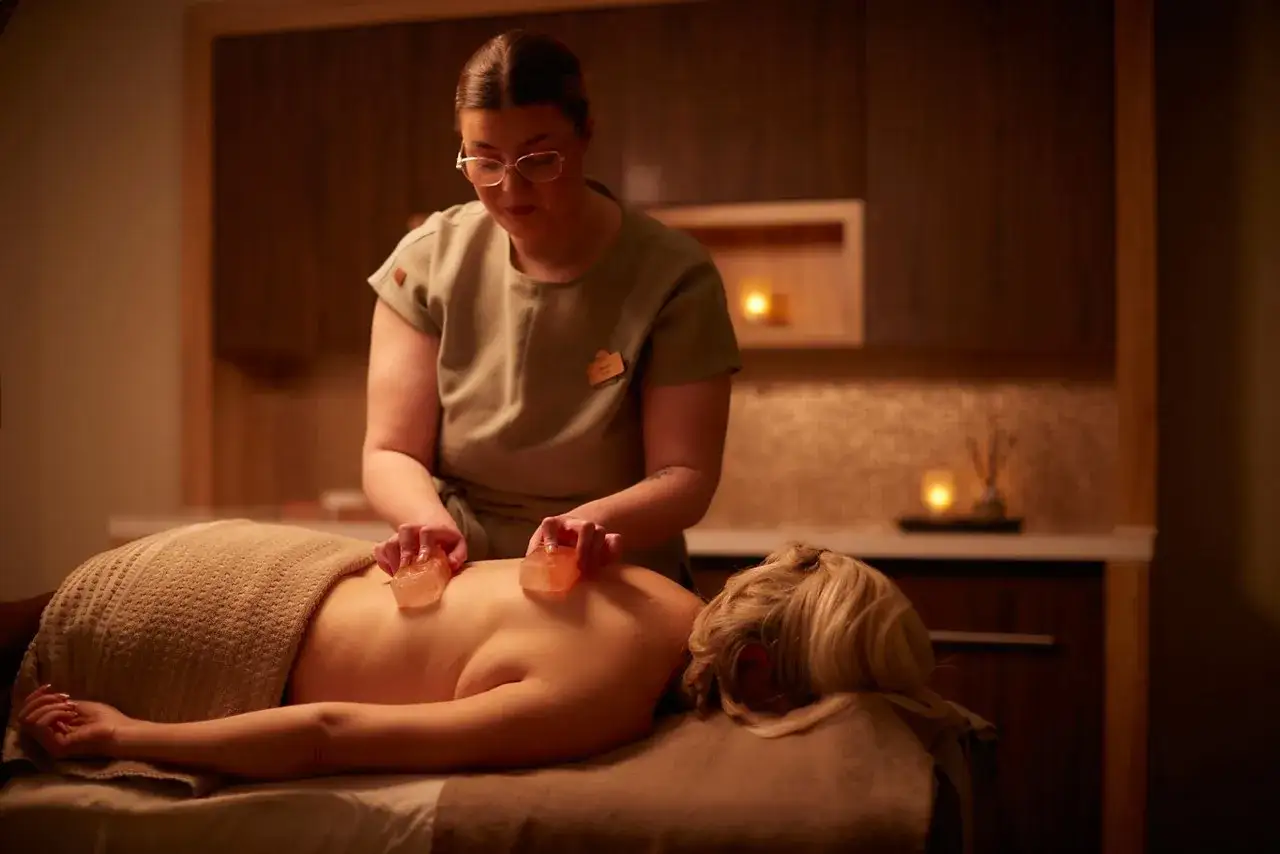 A therapist uses warm salt stones on a client's back, offering a unique experience of what is a salt sauna.