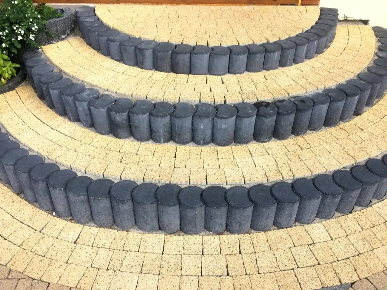 Okrągła palisada betonowa tworzy efektowne schody tarasowe.