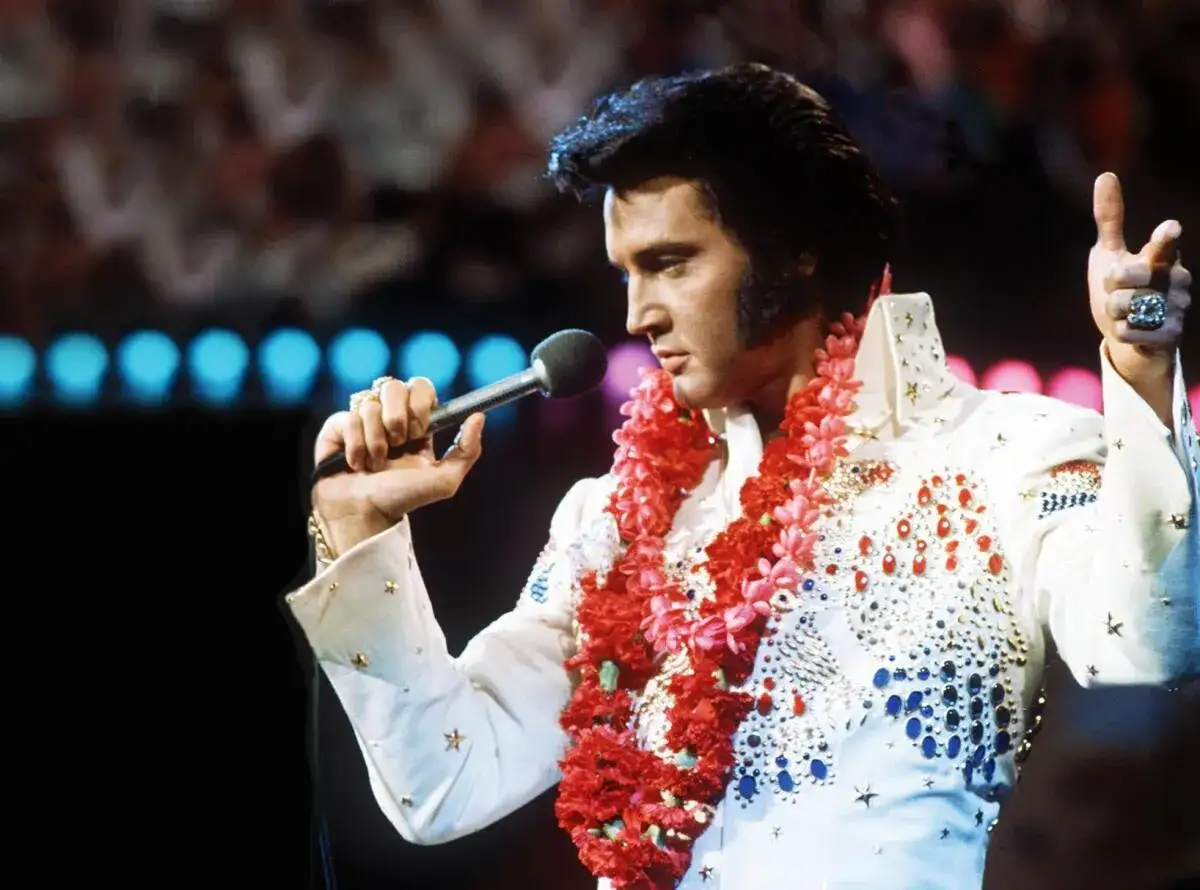 Elvis Presley, mit einer Blumenkette, singt auf der B&uuml;hne. Ein ikonischer Moment von Elvis Hawaii.