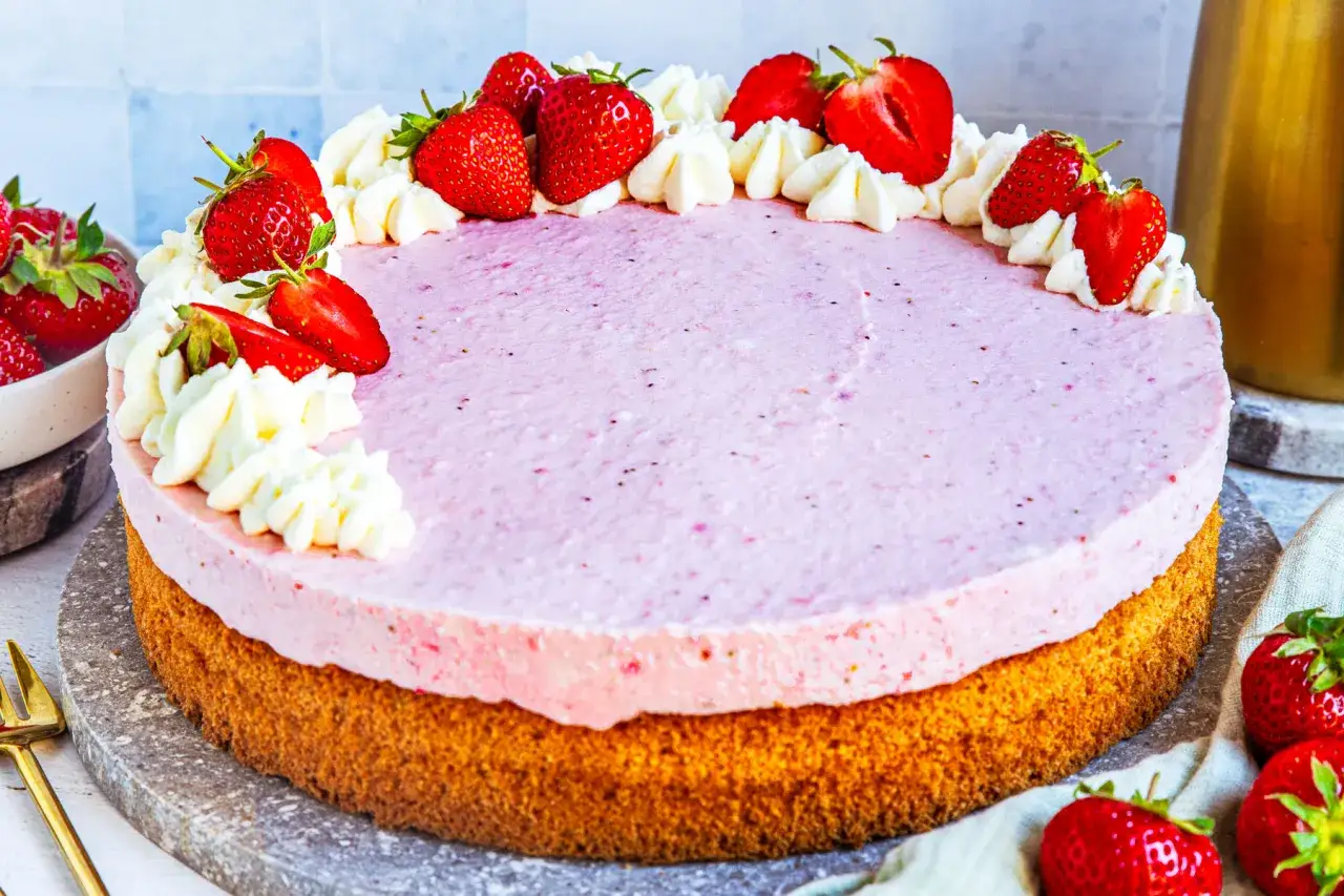 Eine köstliche Erdbeer Joghurt Torte mit frischen Erdbeeren und Sahnetupfern, bereit zum Genießen.