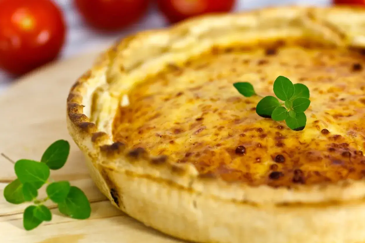 Une délicieuse quiche sans œuf, dorée et garnie de quelques feuilles de persil frais. Parfaite pour un repas léger.