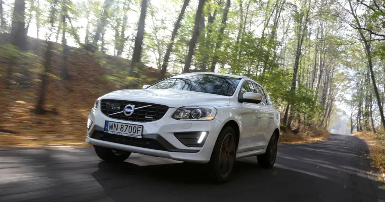 Białe Volvo XC60 T5 jedzie leśną drogą jesienią.