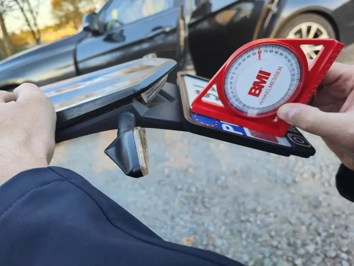 Sprawdzanie kąta mocowania tablicy rejestracyjnej motocykl przepisy. Czerwony kątomierz BMI na tablicy.