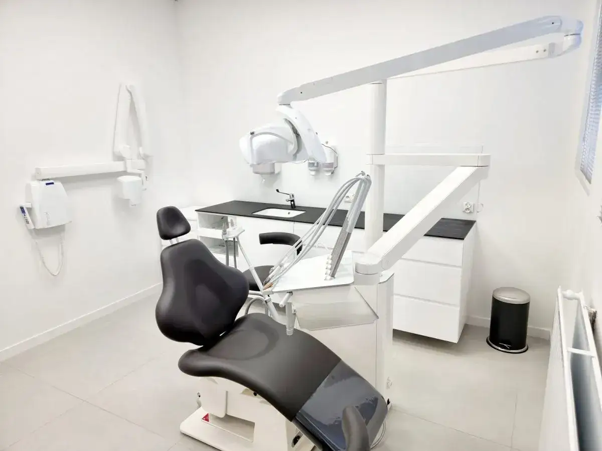 Nowoczesny gabinet stomatologiczny z fotelem dentystycznym i lampą zabiegową.