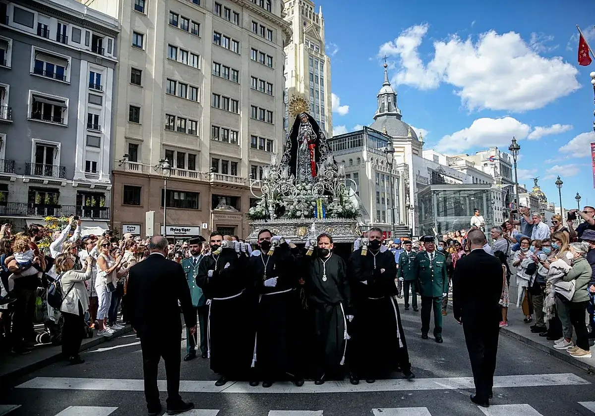 Procesión del Encuentro en Madrid. Hombres portan un paso con la Virgen, rodeados de fieles y autoridades.