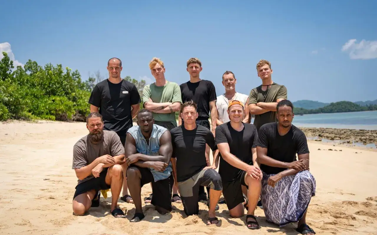 Grupp av tio män på en sandstrand, redo för en utmaning. Kanske är det en ny säsong av Robinson?