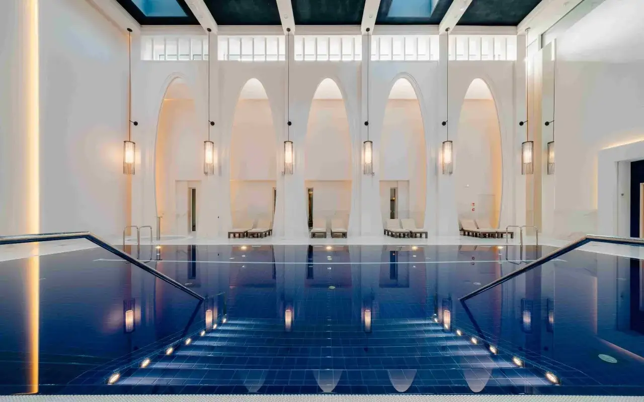 Elegancki basen w hotelu Pieniny Grand z podświetlanymi schodami i leżakami.