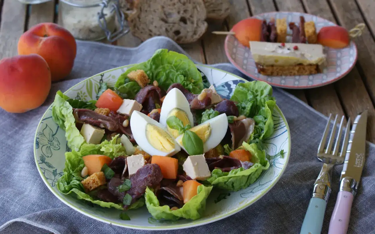 Salade périgourdine : laitue, dés de foie gras, magret fumé, œuf dur, croûtons et fruits secs. Un délice !