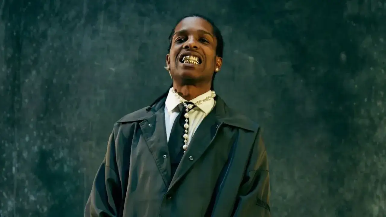 ASAP Rocky Polska: raper w białej koszuli, czarnym krawacie i perłach, z błyszczącymi zębami.