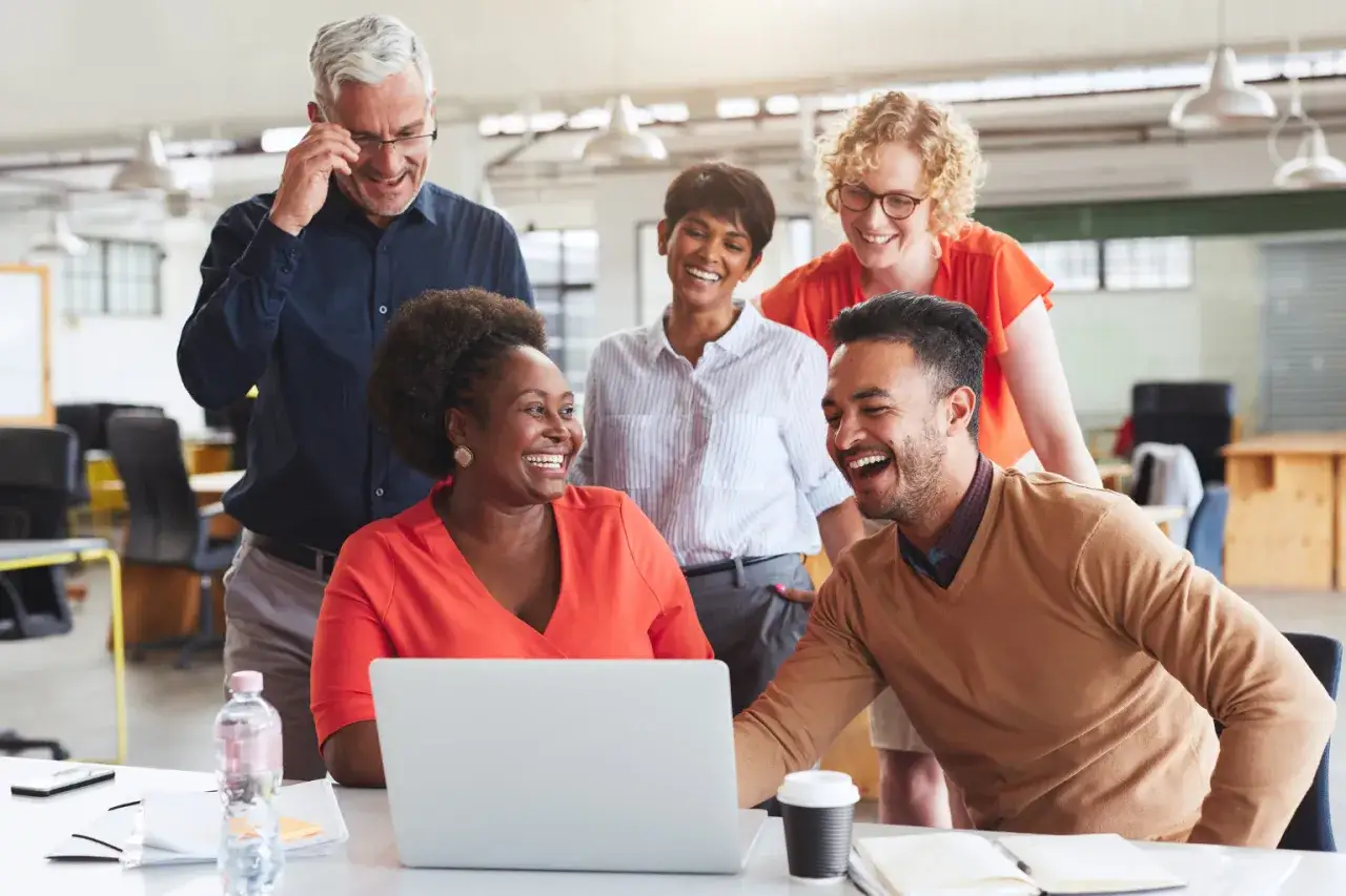 A diverse team laughs together, showcasing the benefits of equality, diversity, and inclusion in the workplace.