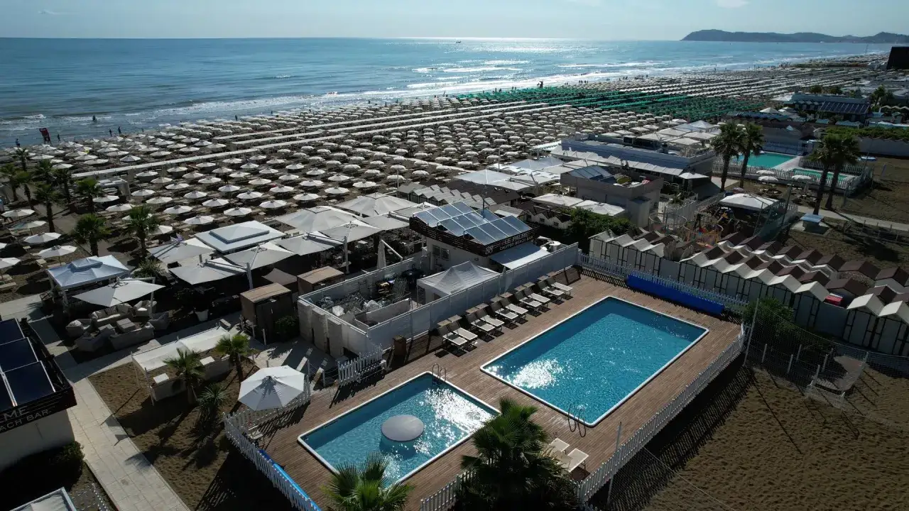 Vista aerea del Bagno 88 Riccione con piscine, lettini, ombrelloni e cabine sulla spiaggia.