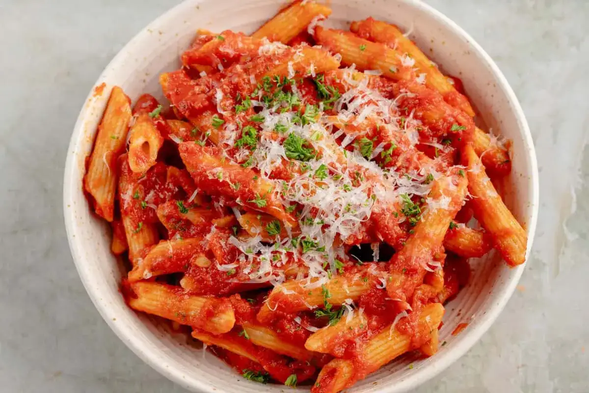 Penne all'arrabiata co to? Pikantny sos pomidorowy z czosnkiem i papryczką chili, posypany parmezanem i natką pietruszki.