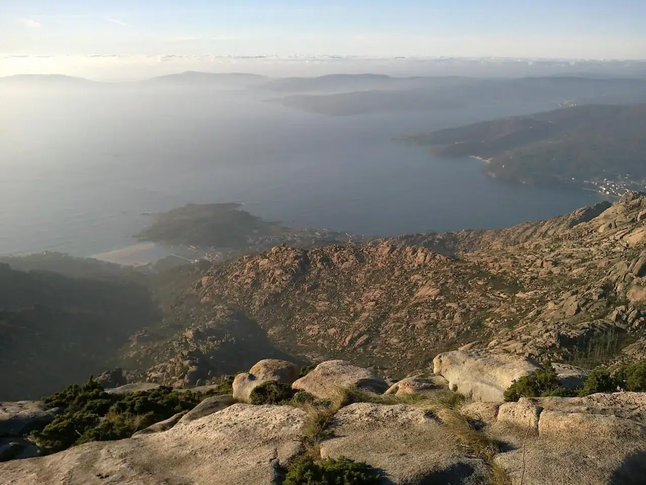 Vista desde el monte Pindo, con el mar y las islas al fondo. Rocas y vegetación en primer plano.
