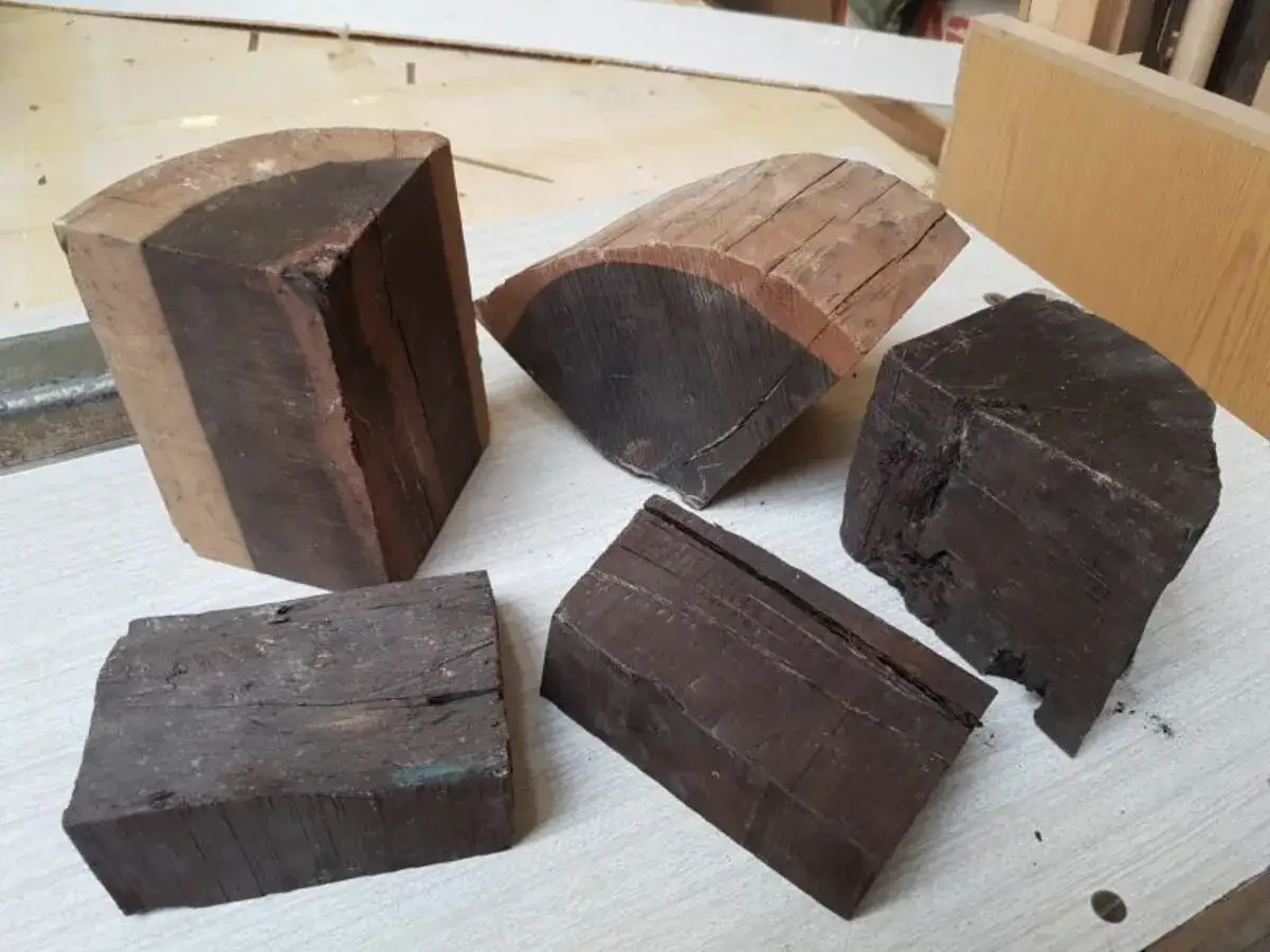 Bloques de madera ebano, algunos con vetas claras, listos para ser tallados.
