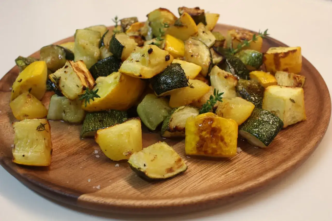 Assiette de courgettes au four, coupées en dés et parsemées de thym frais. Les légumes sont légèrement caramélisés, offrant une texture appétissante.