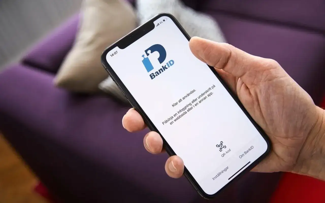 En hand h&aring;ller en mobil med BankID-appen &ouml;ppen. Var f&ouml;rsiktig med misst&auml;nkta SMS som kan leda till phishing.