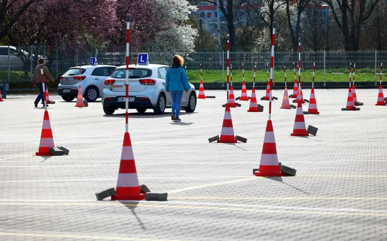 Plac manewrowy z pachołkami i samochodami z literą L. To miejsce, gdzie nauczysz się, jak zdać egzamin na prawo jazdy.